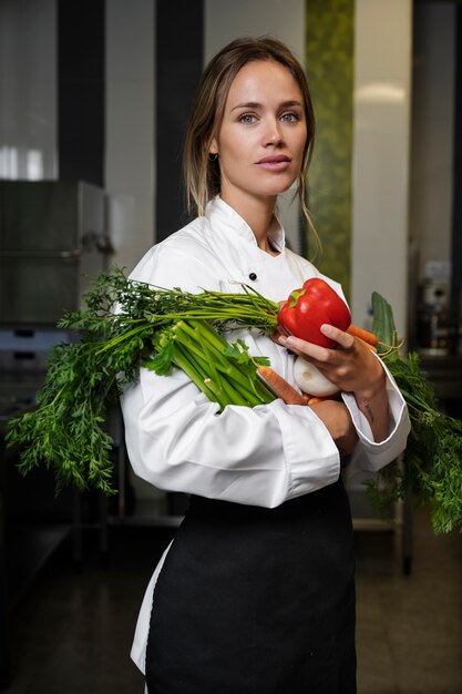 Female chef in the kitchen holding vegetables