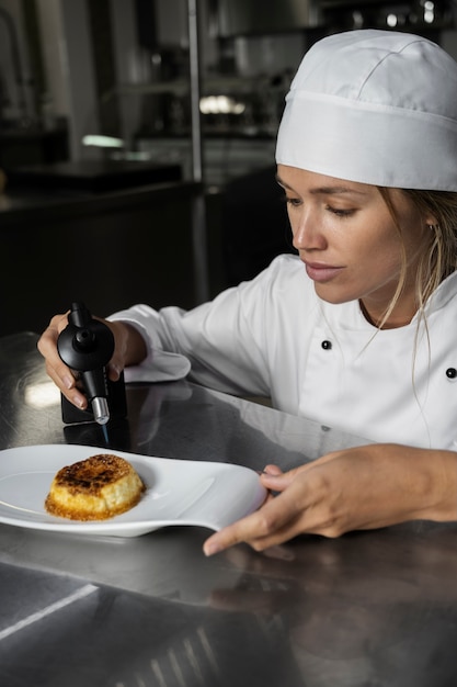 Free photo female chef in the kitchen torching dessert