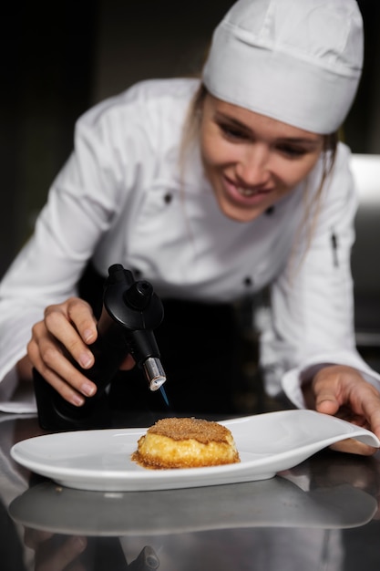 Free photo female chef in the kitchen torching dessert