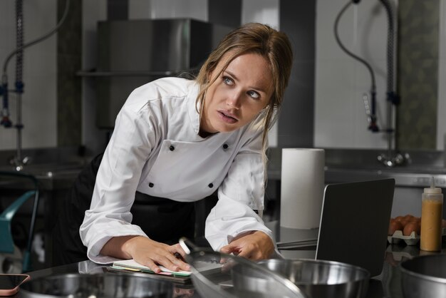 Female chef in the kitchen using laptop device