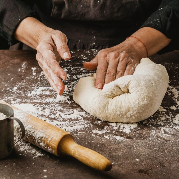 Женский шеф-повар замешивает тесто для пиццы