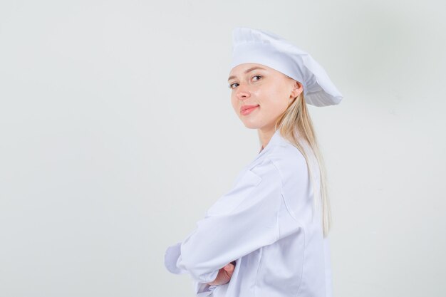 Cuoco unico femminile che guarda l'obbiettivo con le braccia incrociate in uniforme bianca e guardando fiducioso. vista frontale.