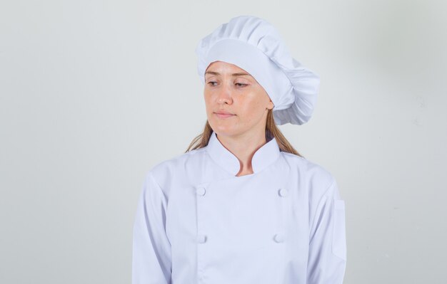 Женщина-повар смотрит вниз в белой форме