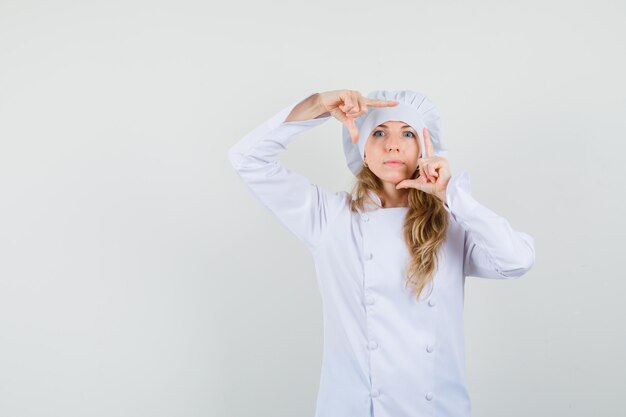 Female chef making frame gesture in white uniform 