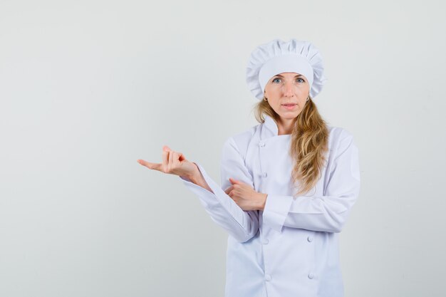 Female chef pointing to the side in white uniform 