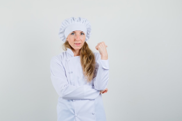 Female chef pointing thumb up back in white uniform and looking sensible