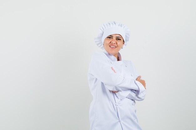 Female chef posing while standing in white uniform and looking confident