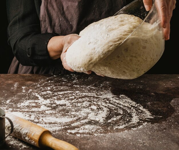 밀가루로 덮여 테이블에 피자 반죽을 붓는 여성 요리사