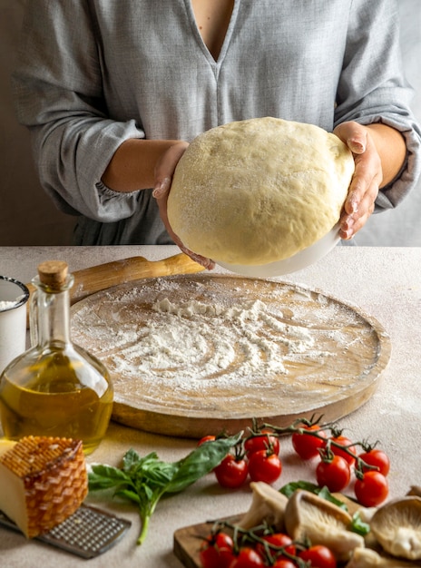 Female chef preparing dough for pizza