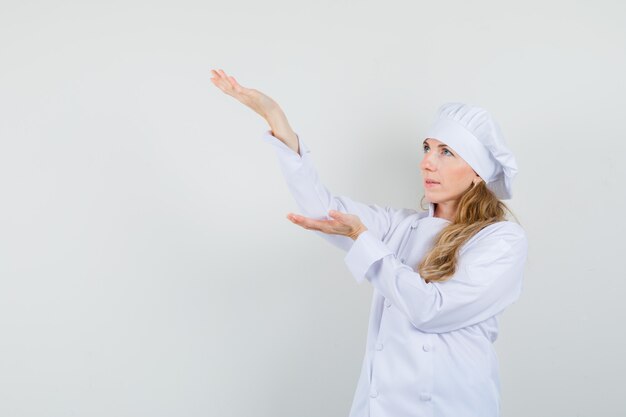 白い制服に何かを持っていると手のひらを上げると集中して見える女性シェフ