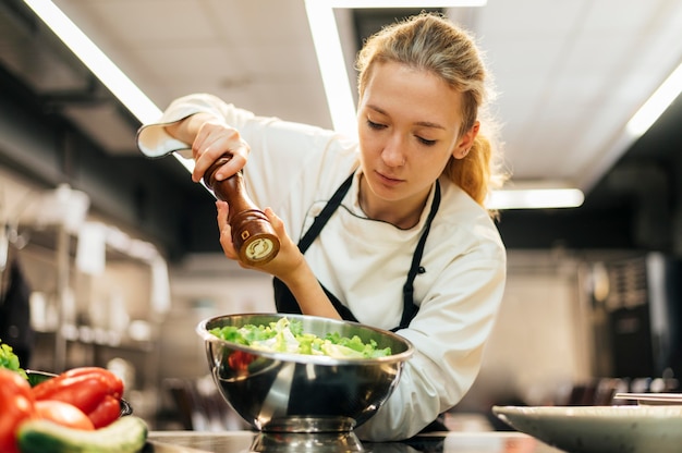 Free photo female chef seasoning salad