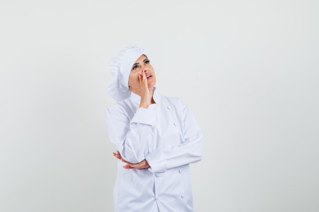 Female chef shouting to somebody while looking up in white uniform 