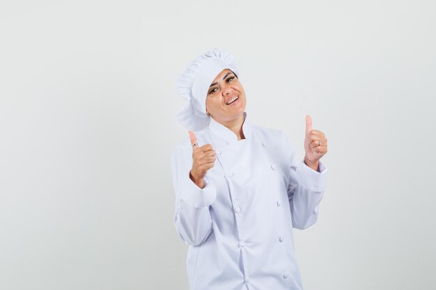 Female chef showing double thumbs up in white uniform and looking confident