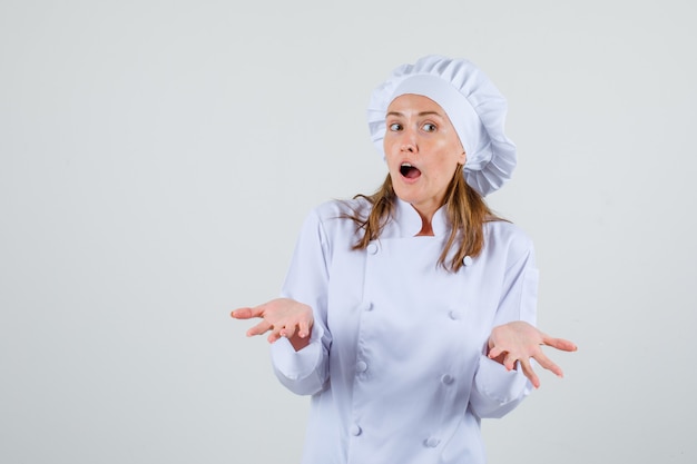 Female chef showing helpless gesture in white uniform and looking confused. front view.