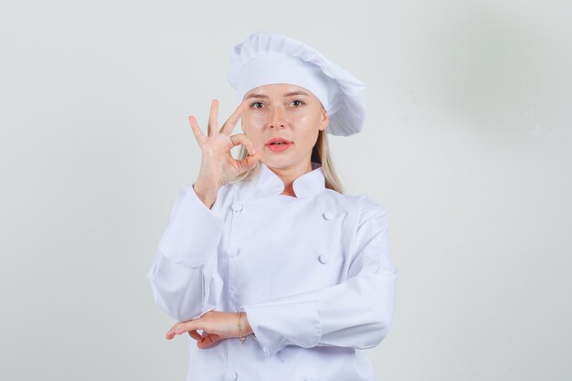 흰색 유니폼에 확인 제스처를 보여주는 여성 요리사 자신감을 찾고