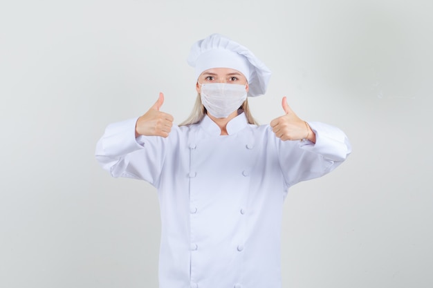 Female chef showing thumbs up in white uniform and looking pleased 
