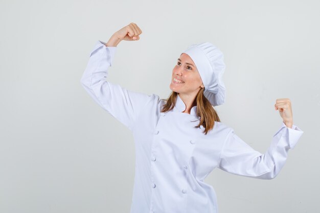 Female chef showing winner gesture in white uniform and looking cheerful