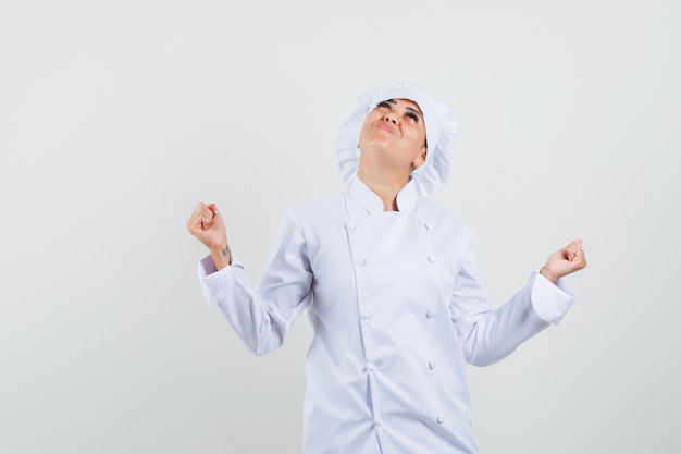 Female chef showing winner gesture in white uniform and looking happy