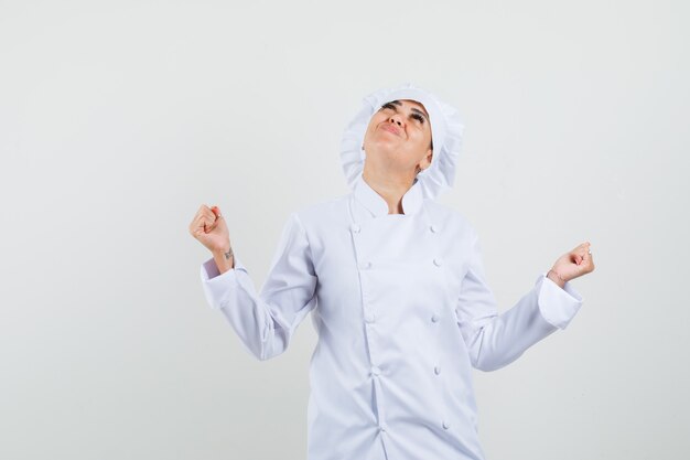 Female chef showing winner gesture in white uniform and looking happy