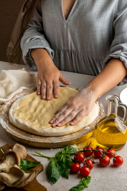 Женский шеф-повар, растягивая тесто для пиццы руками