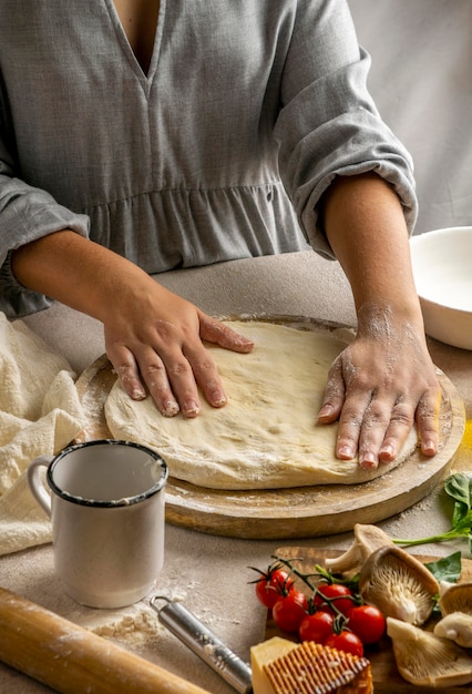 Женщина-повар растягивает тесто для пиццы