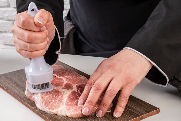 Female chef tenderizing meat