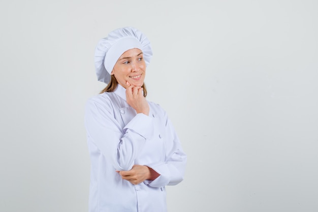 Female chef thinking and looking aside in white uniform and looking glad