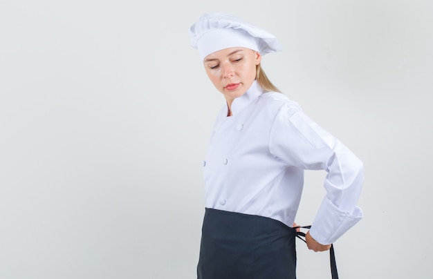 Female chef tying up apron around waist in white uniform