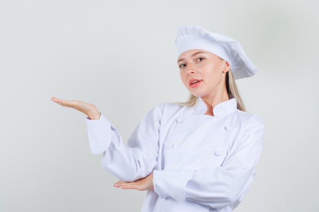 여성 요리사 환영 또는 흰색 유니폼에 뭔가를 보여주는 쾌활한 찾고