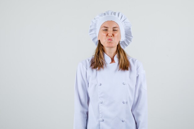 Female chef in white uniform frowning her face and looking irritated