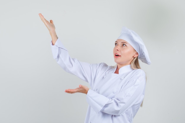 Female chef in white uniform gesturing like holding something 