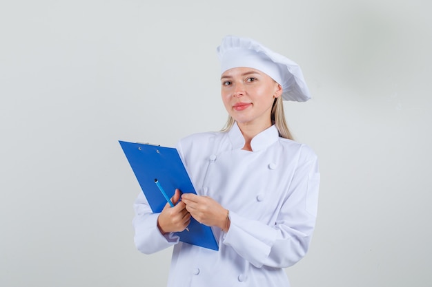 흰색 유니폼 클립 보드와 연필을 들고 기뻐 보이는 여성 요리사