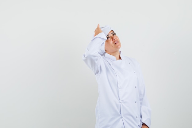 Female chef in white uniform holding hand on head and looking sorrowful