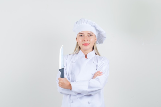 Женщина-повар в белой форме держит нож и улыбается