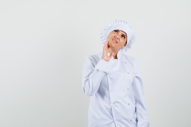 Cuoco unico femminile in uniforme bianca che osserva in su e che sembra pensieroso