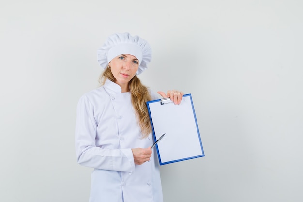 Cuoco unico femminile in penna che indica uniforme bianca una lavagna per appunti e che sembra ragionevole