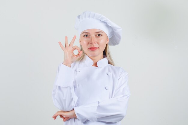 Female chef in white uniform showing ok sign and looking positive 