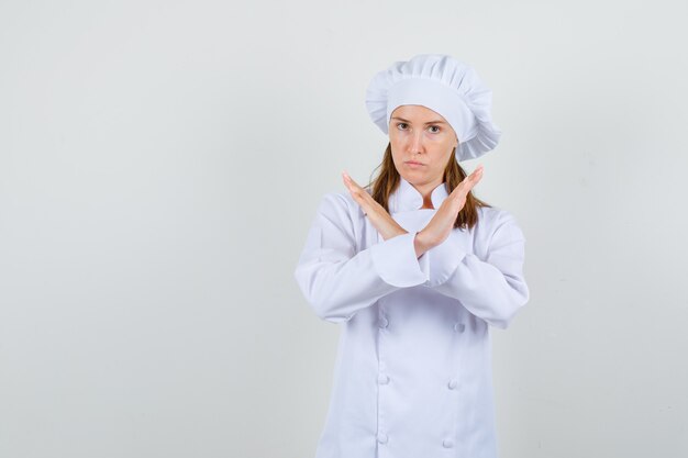 Female chef in white uniform showing stop gesture and looking serious