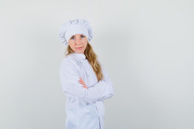 Female chef in white uniform standing with crossed arms and looking confident 