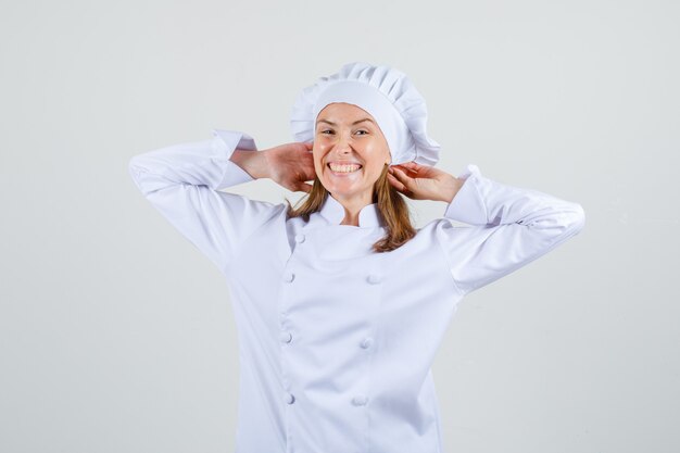 머리 주위에 팔을 스트레칭 하 고 기뻐 보이는 흰색 제복을 입은 여성 요리사