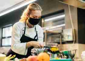 Foto gratuita cuoco unico femminile con maschera per affettare frutta