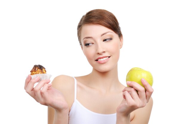 Female choice  high-calorie cake or healthy apple on white