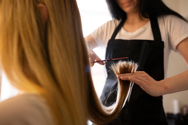 女性のクライアントがヘアカッターでを切っている