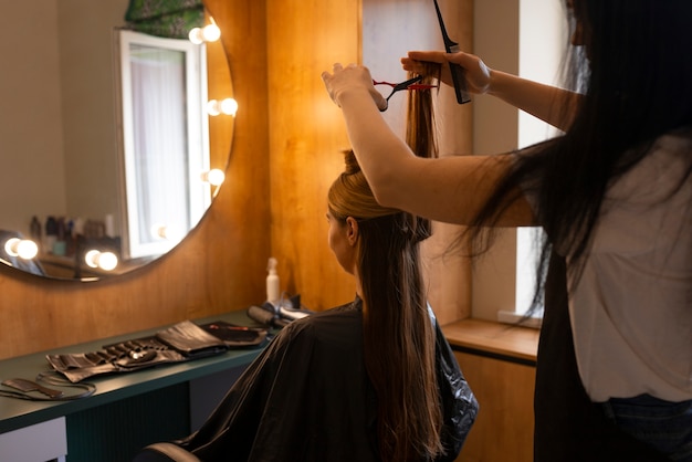 女性のクライアントがヘアカッターでを切っている