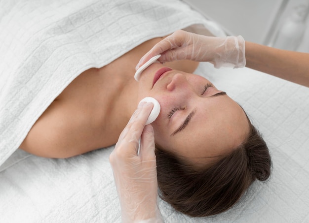 Foto gratuita cliente femminile al salone per routine di cura del viso con dischi detergenti