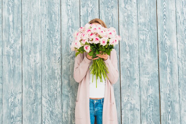 Female closing face by bouquet of roses