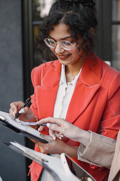 Foto gratuita colleghe che discutono i dati nella caffetteria all'aperto. donne multirazziali che analizzano la strategia produttiva per la proiezione aziendale utilizzando documenti in street cafe