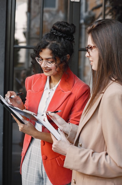 Free photo female colleagues discussing data in the cafe outdoor. multiracial female persons analyzing productive strategy for business projecting using documents in street cafe