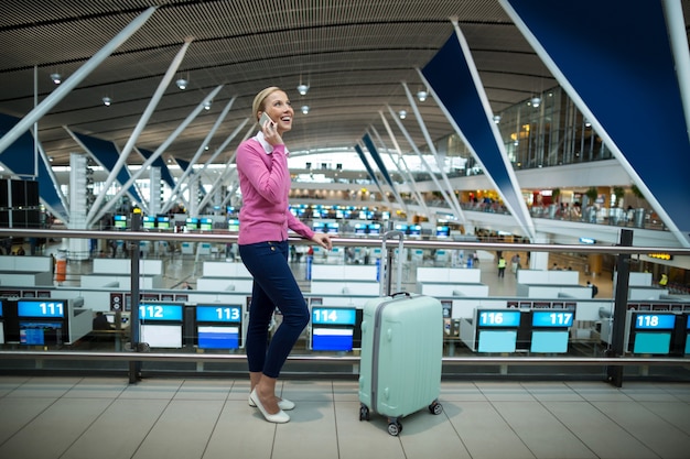 Free photo female commuter with luggage talking on mobile phone