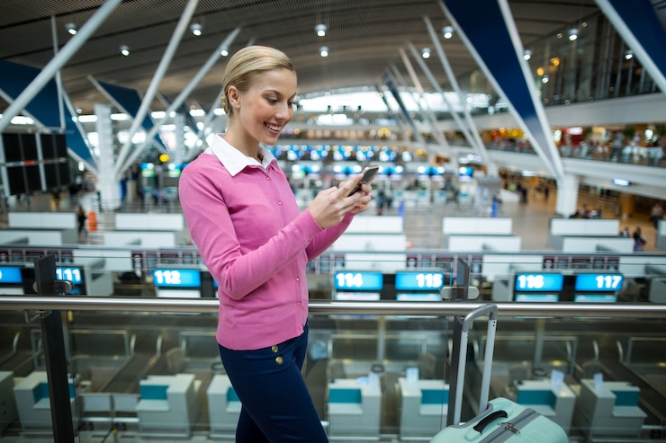 Free Photo female commuter with luggage using mobile phone